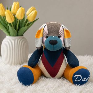 Patchwork memory puppy with floppy ears beside a vase of yellow tulips