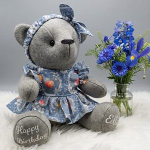 Small grey memory bear wearing a blue floral dress and matching headband