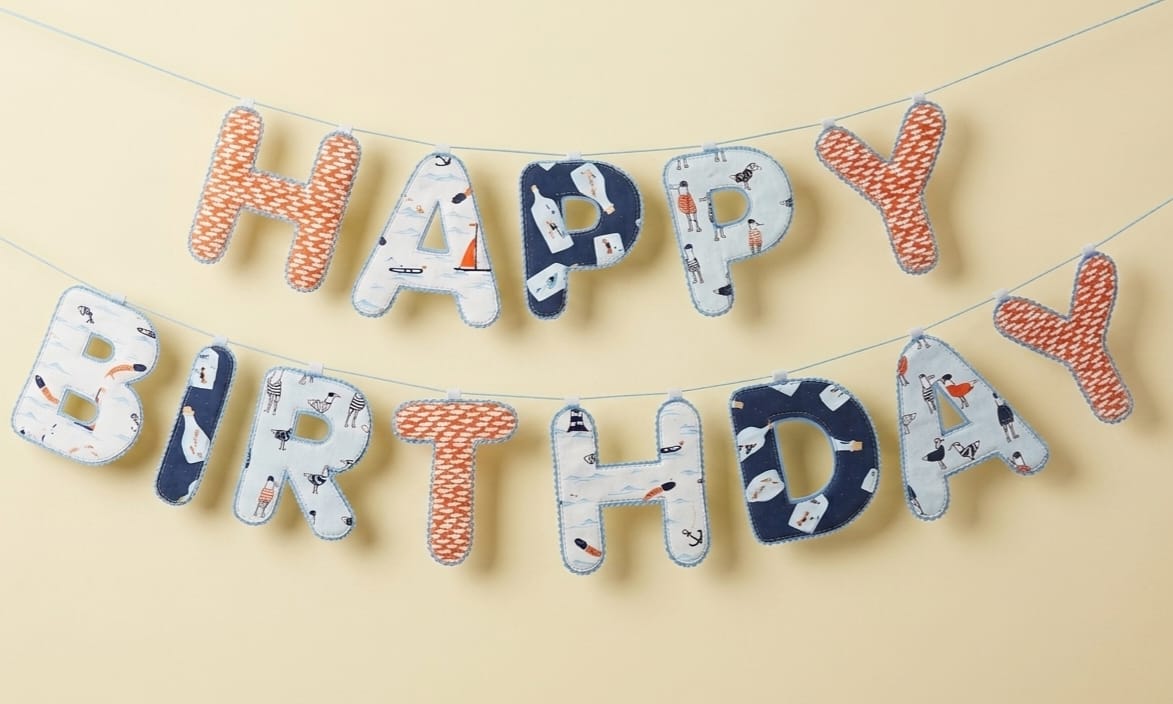 Blue patterned Happy Birthday fabric banner hung in two rows